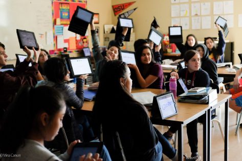Dual language students holding up tablets in class