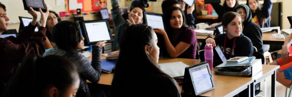 Dual language students holding up tablets in class